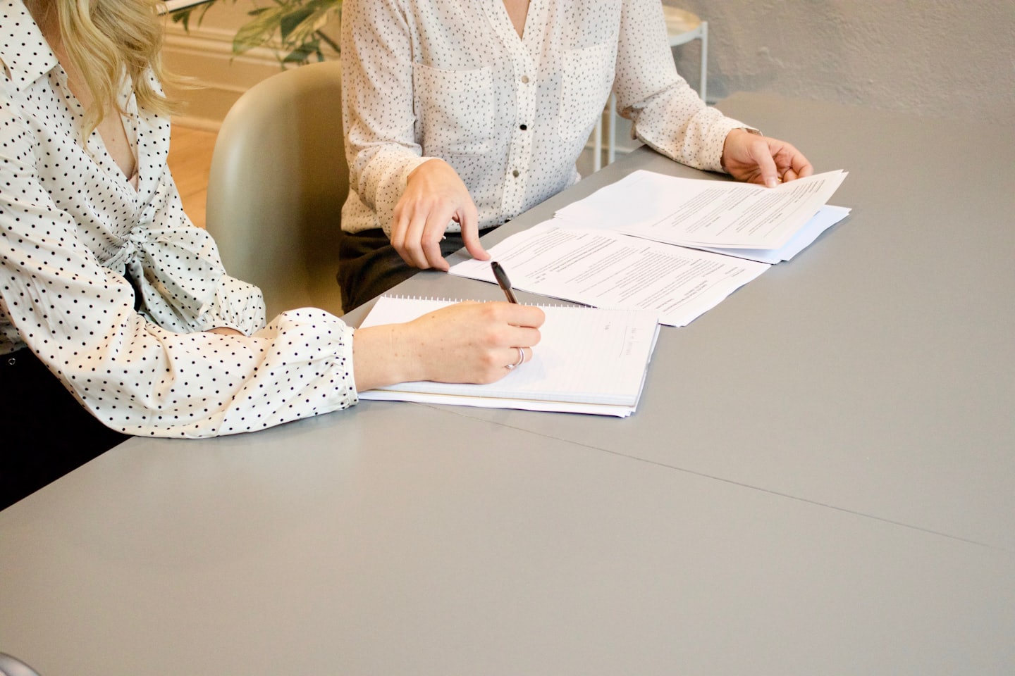 Zwei Personen gehen am Tisch Unterlagen durch und unterschreiben ein Dokument